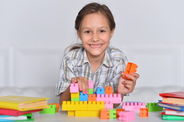 Porait of happy cute little girl playing with cubes