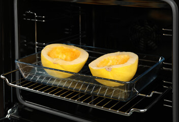 Baking dish with halves of fresh spaghetti squash in oven