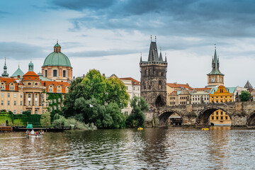 Fototapeta premium Charles Bridge,tourist boat on Vltava river,Prague, Czech Republic. Buildings and landmarks of Old town on summer day. Amazing European cityscape.Popular tourist destination.Colorful urban city scene
