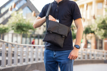 Gangster man takes a gun from the messenger bag in a city