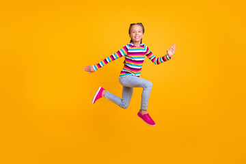 Fototapeta na wymiar Photo of carefree runner sporty girl jump hurry fast wear striped shirt jeans shoes isolated yellow color background