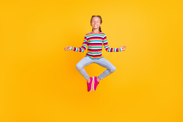 Fototapeta na wymiar Photo of peaceful girl jump meditate close eyes wear striped shirt jeans shoes isolated yellow color background