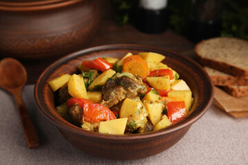 Tasty cooked dish with potatoes in earthenware on table