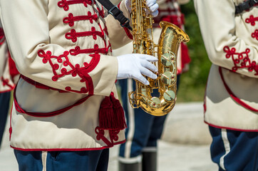 Golden saxophone. Stage, Shipka. A man is playing the saxophone. A musician from a military band plays the saxophone. Military parade uniform. A police band plays on Shipka Peak, Bulgaria.