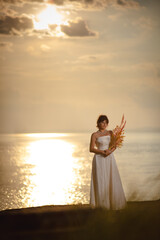 Beautiful bride in white wedding dress at sunset near a beach and the ocean or sea coast in United Kingdom