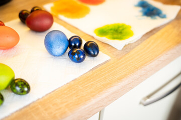 Freshly painted green, blue, red and orange Easter chicken and quail eggs lie in the kitchen
