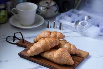 croissant on a brown plate next to a mug of milk on marble background