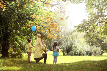 Family with children for a walk in the summer park. Сoming autumn in the park. Family. Fall. Happiness.