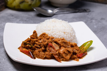 Stir-fried tuna with curry paste and steamed rice in a white plate