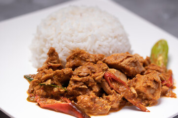 Stir-fried tuna with curry paste and steamed rice in a white plate