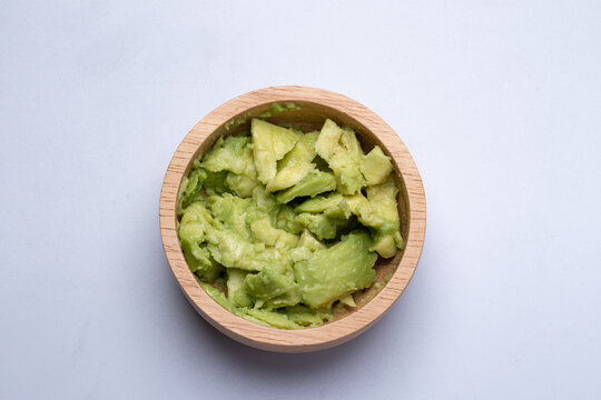 Mashed Avocado In A Wooden Cup On White Background