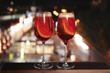 Glasses of cocktails on wooden surface against blurred cityscape. Modern outdoor terrace