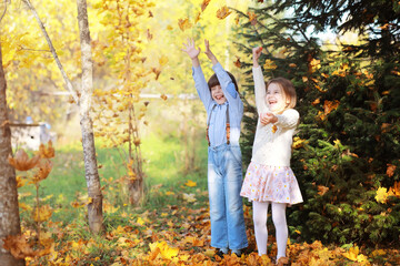 Fototapeta premium Young family on a walk in the autumn park on a sunny day. Happiness to be together.