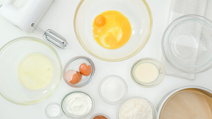 Egg yolks, egg whites, flour, sugar, and some ingredients for cake recipe close up on kitchen table. Homemade chocolate cake step by step baking process
