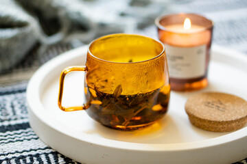 Cup of tea and cozy burning candle on white tray