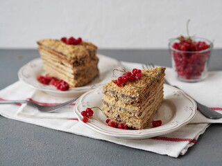 Two pieces of honey puff cake with red currant berries on a gray background. Food background.