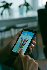 man searches schools online with his smartphone