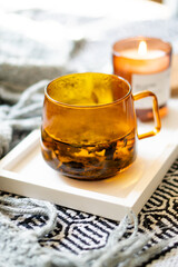 Cup of tea and cozy burning candle on white tray