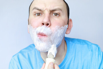 A man shaves in front a mirror. Shaving foam. Disposable razor.