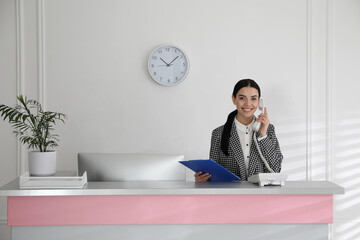 Receptionist talking on phone at countertop in office