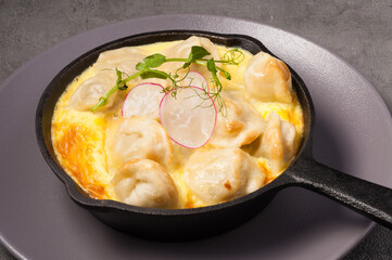 dumplings baked in an omelet in a frying pan, decorated with radishes and micro-greens