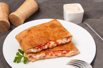 pancakes with ham, cheese and tomatoes on a white plate. horizontal frame