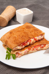 pancakes with ham, cheese and tomatoes on a white plate. vertical frame