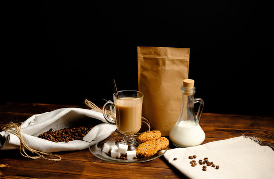 a cup of coffee with a jug of milk, cookies and sugar