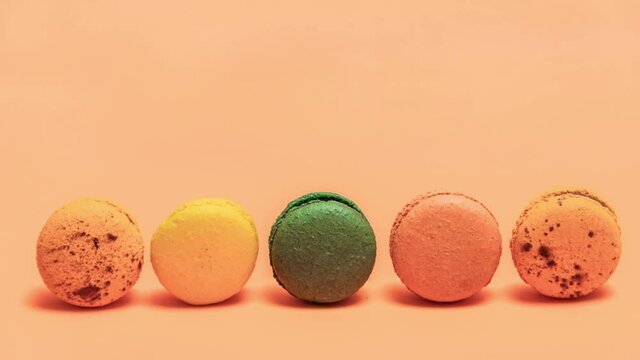 Macaroons rolling on an orange background. Stop motions animation.