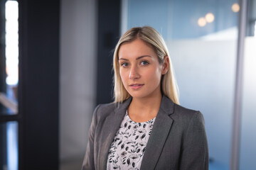Portrait of caucasian businesswoman wearing gray jacket and looking at camera