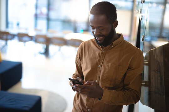 Smiling african american businessman using smartphone and wearing formal clothes