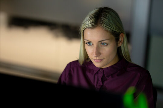 Caucasian businesswoman working at night using laptop