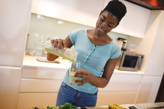 Smiling african american woman in kitchen preparing health drink