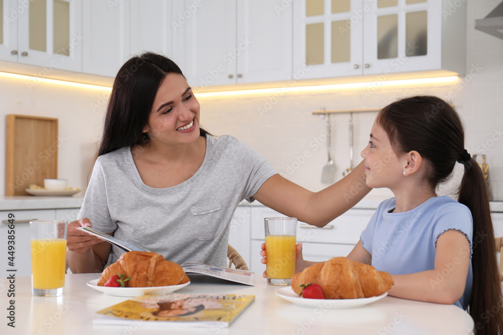 Wall mural Happy mother and daughter having breakfast together in kitchen. Single parenting