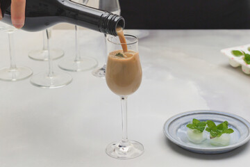 Cream liquor with frozen ice mint leaves close up in glasses on light background, vertical banner