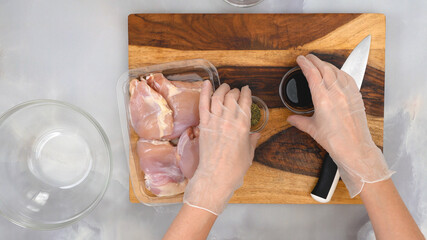 Chicken meat, soy sauce, and seasoning close up on wooden board. Woman cooking sour cream chicken paprika, step by step preparation process.