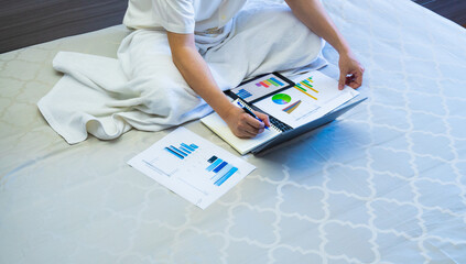 business man work with chart or graph report and note on notebook on bed