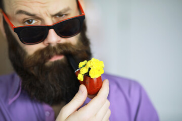 Handsome man or lumberjack, bearded hipster, with beard and mustache in shirt with smoking pipe