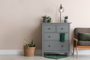 Room interior with grey chest of drawers near beige wall