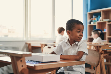 Fototapeta premium Calm boy behaving quietly at the school lesson