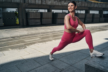 Fototapeta na wymiar Pleased sportive adult woman practising leg stretches
