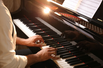 Man playing piano indoors, closeup. Talented musician