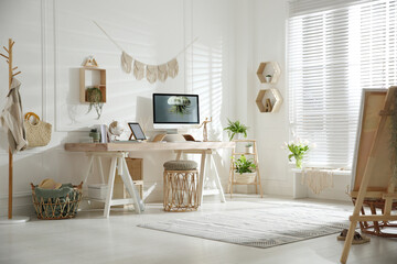 Stylish home office interior with comfortable workplace and easel