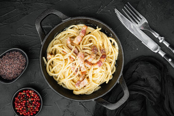 Carbonara pasta dish. Traditional Roman cuisine. Italian food, in cast iron frying pan, on black...