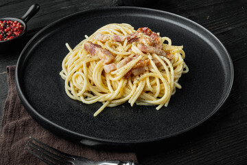 Carbonara pasta dish. Traditional Roman cuisine. Italian food, on black wooden background