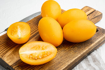 Yellow whole tomato with a slice, on white stone table background