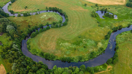 Aerial landscape of winding river in green field, top view of beautiful nature background from drone, seasonal summer landscape with copy space.