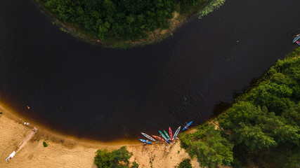 Kayaks on the river bank. Tourist kayaking pier. Tourist camp, river pleasure boat pier during a tourist trip. Aerial view.