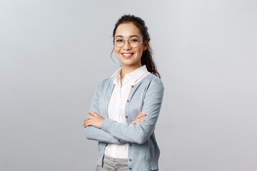 Education, women and lifestyle concept. Attractive asian female entrepreneur, girl tutor smiling satisfied, cross hands chest, pleased help customer with any question, grey background - obrazy, fototapety, plakaty