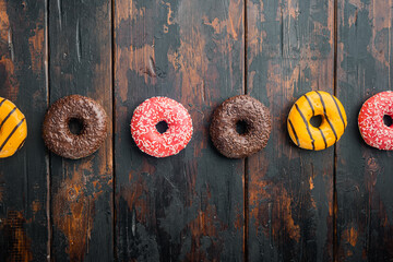 Various decorated donuts set, on old dark  wooden table background, top view flat lay with copy space for text